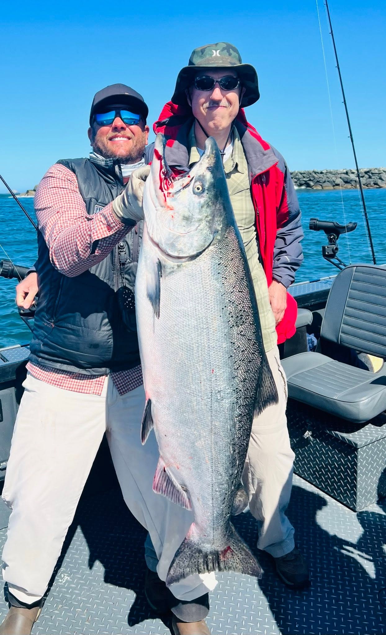 Two anglers holding a large Gold Beach salmon aboard a fishing boat