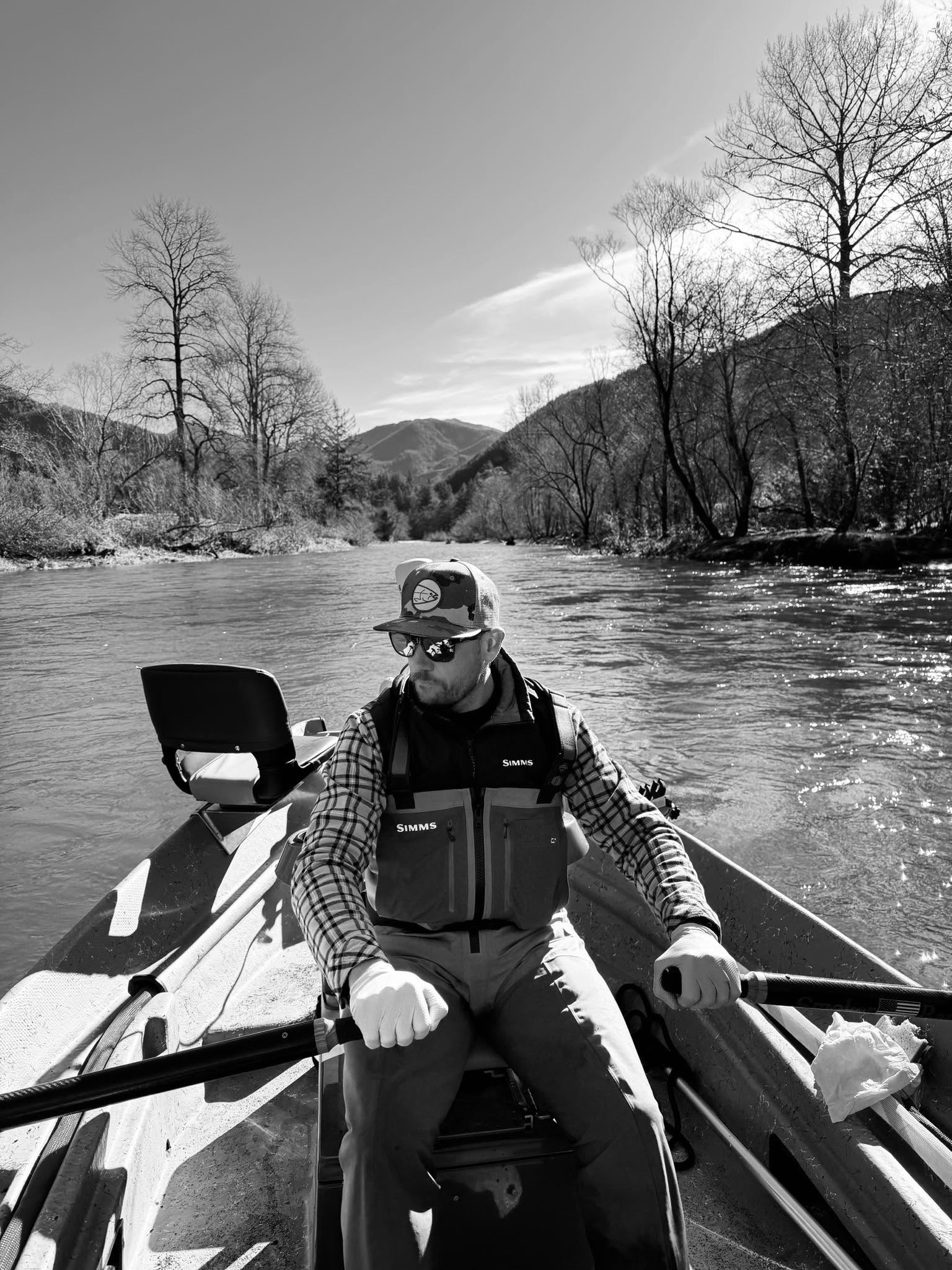 Angler rowing a drift boat through a mountain river in winter