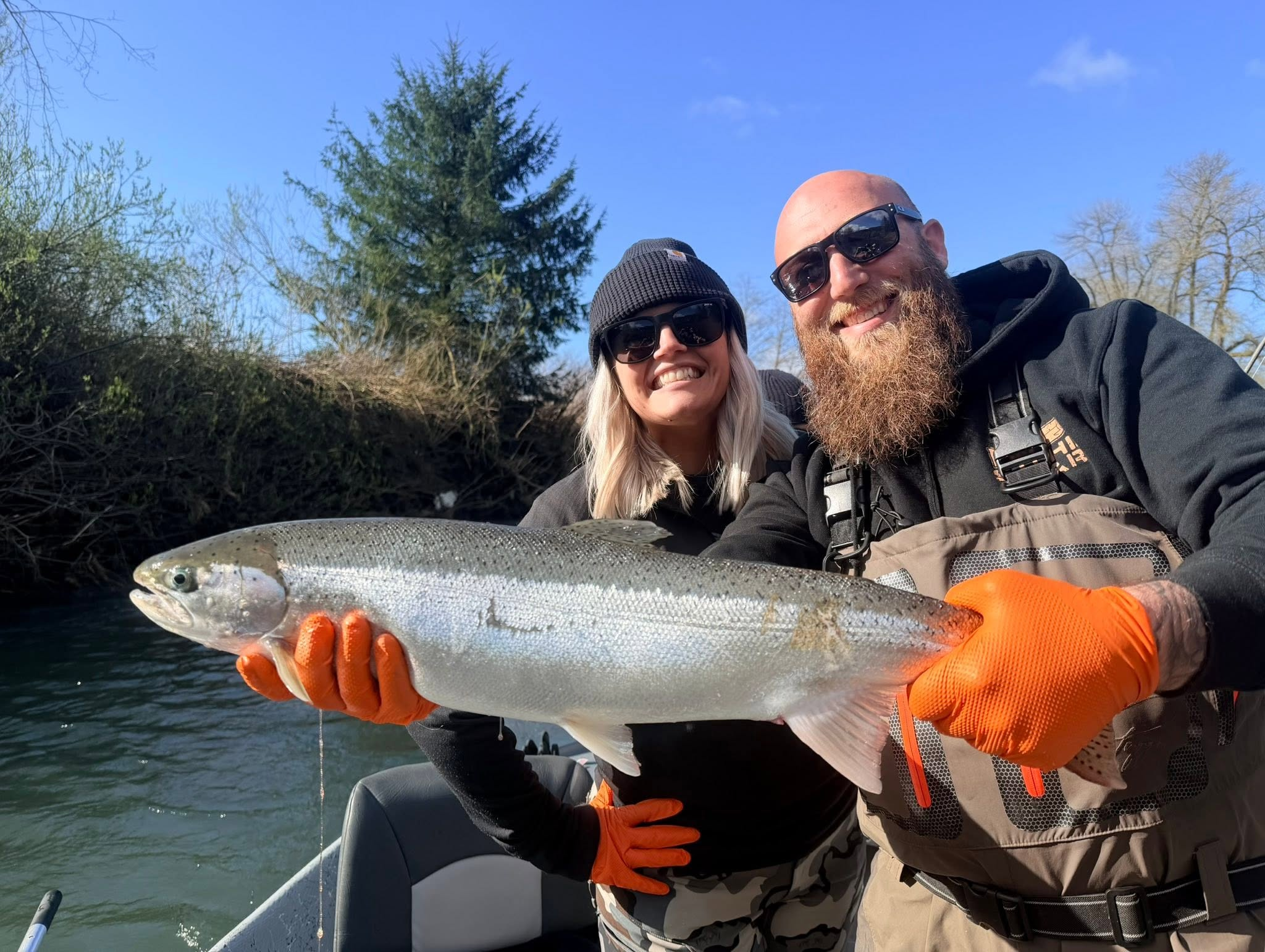 Two anglers holding a winter steelhead during a clear Tillamook-area day